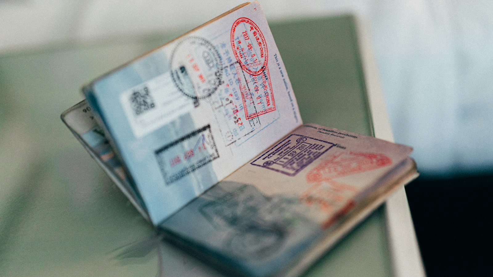 An open passport with colourful ink stamps across its pages